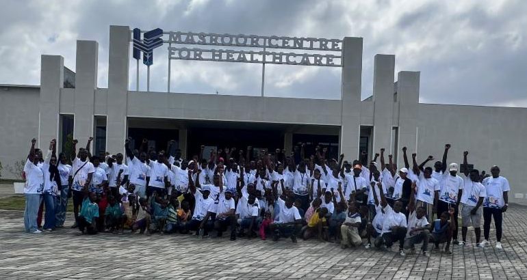 The HF Healthcare Cote d'Ivoire community in the white Walk Run Bike event t-shirts in front of the Masroor Healthcare Centre
