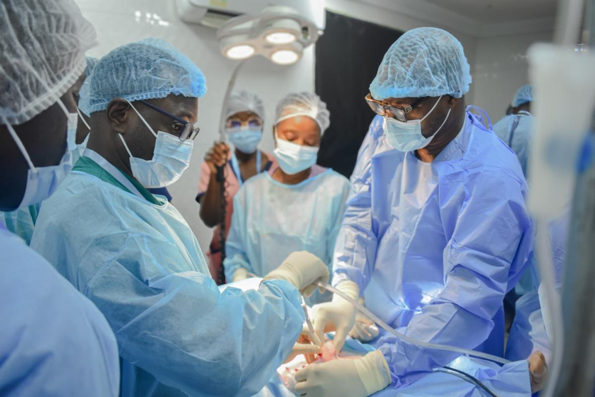 Two people practicing a surgical technique while others observe.