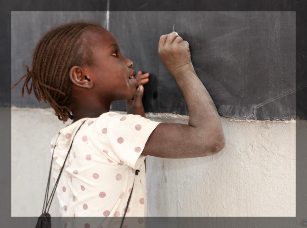 A young girl writing on a chalkboard