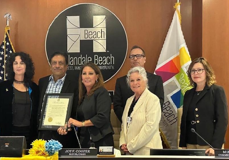 A group of representatives of the City of Hallandale Beach and Humanity First pose with the framed proclamation of the Humanity First USA Beat Hunger Day 2025.