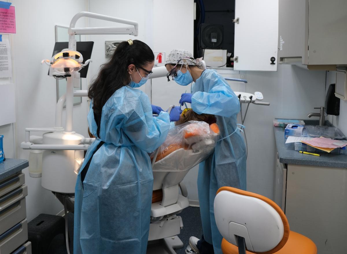 Medical professionals wearing scrubs attend to a patient in a clinic chair.