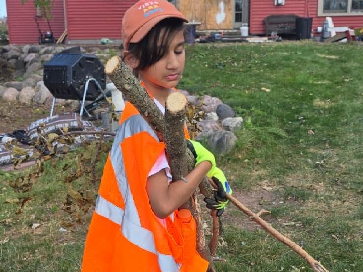 A young Humanity First USA volunteer picks up fallen tree branches in Menasha, Wisconsin.
