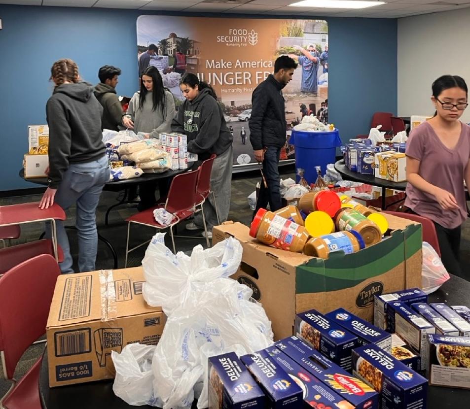 College aged students organize boxes of non perishable food items.