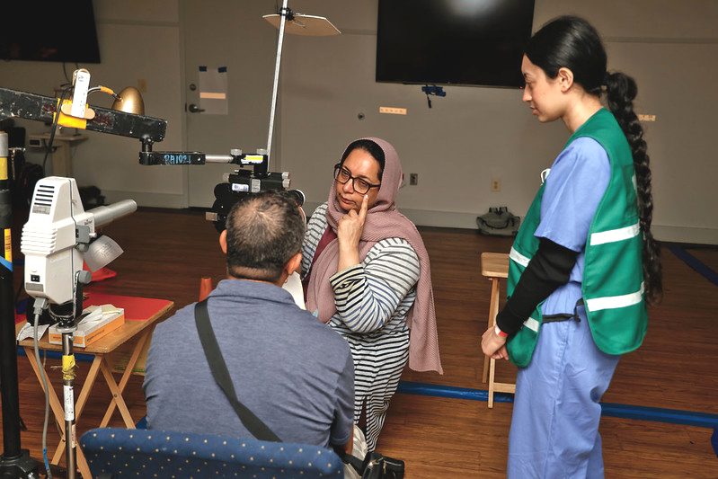 An ophthalmologist speaks to a patient who is seated in front of eye examination equipment.