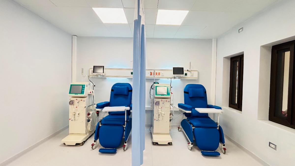 Two blue reclining beds next to dialysis machines are separated by a curtain in the new Dialysis Centre at Nasir Hospital.