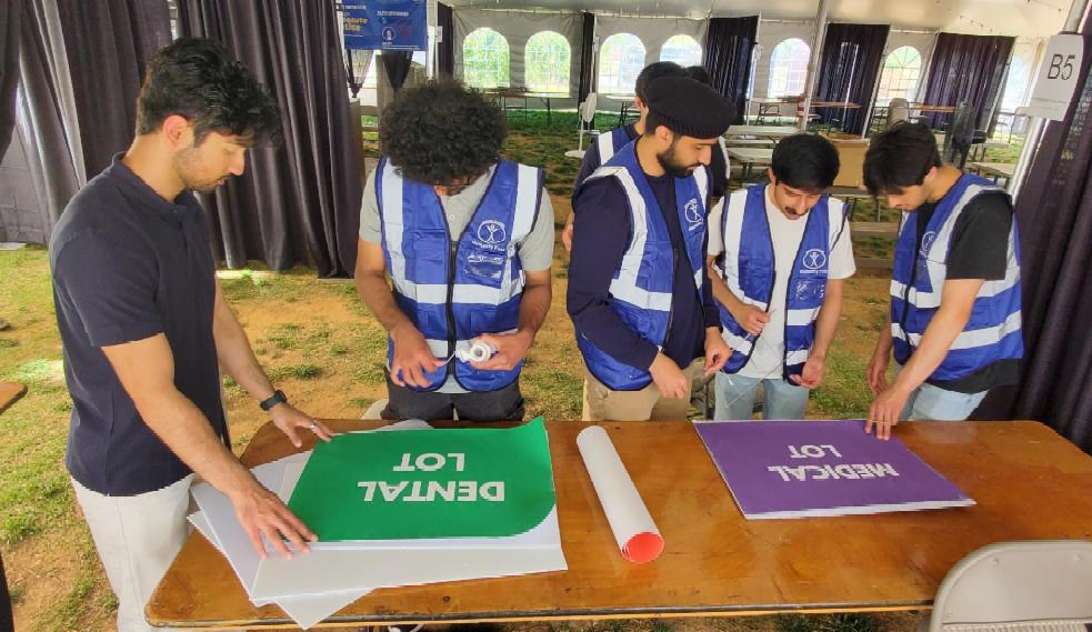 Young men wearing Humanity First vests get signs ready to guide patients through the clinic.