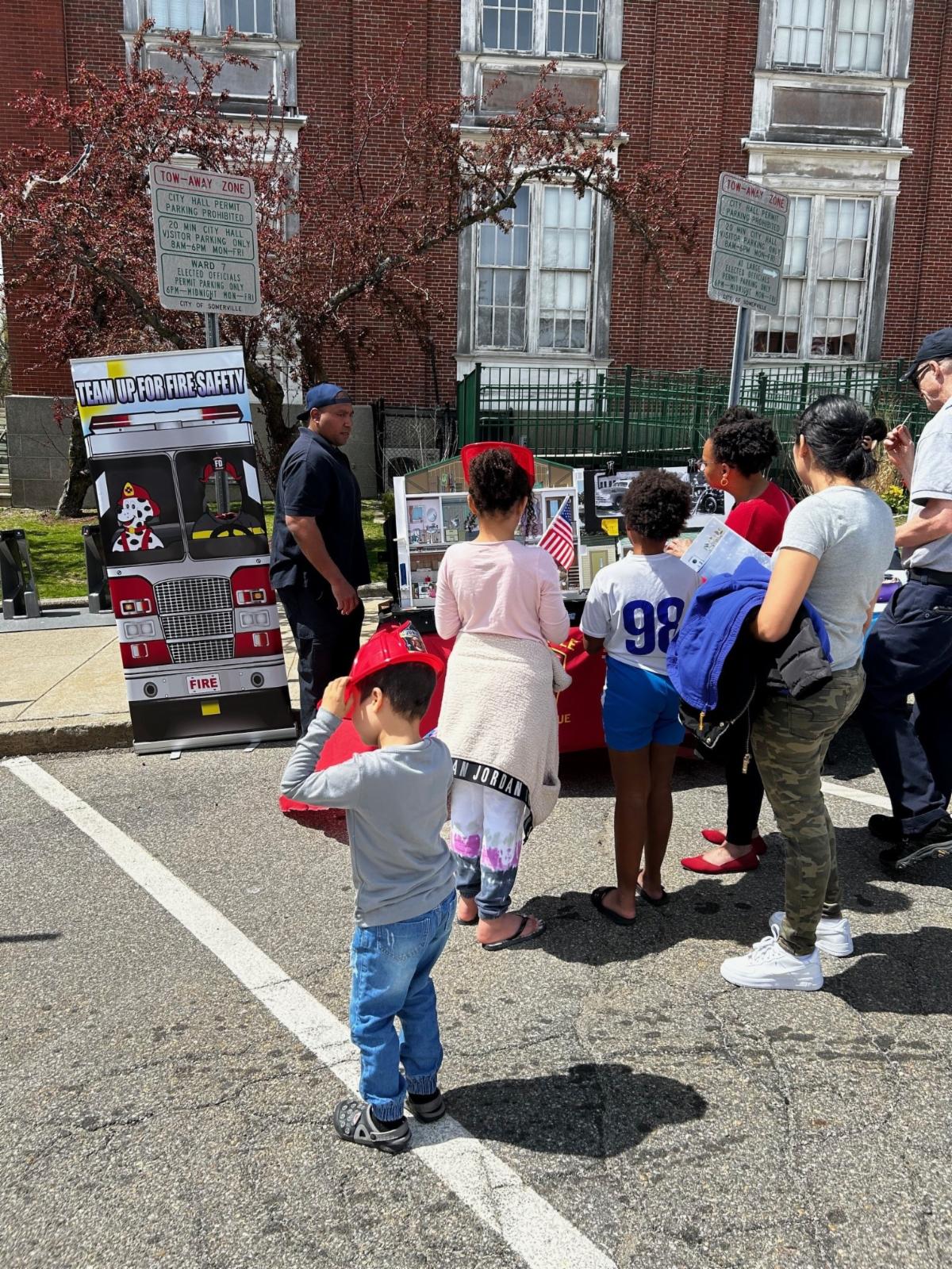 A group of kids meet with firefighters in front of City Hall
