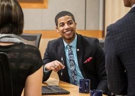 A YOUNG MAN IN A SUIT WORKING WITH HIS TEAM