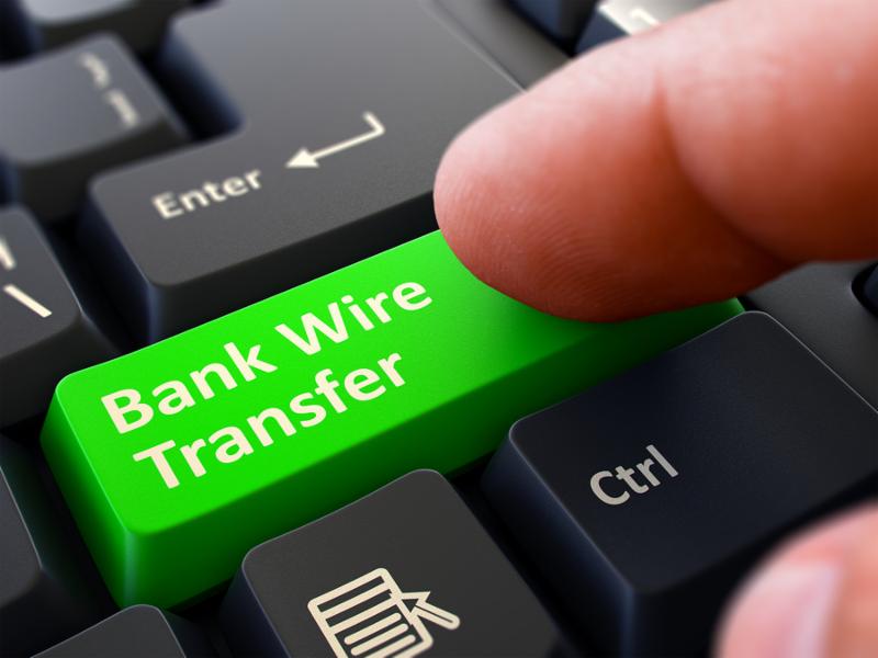 One Finger Presses Green Button Bank Wire Transfer on Black Computer Keyboard. Closeup View. Selective Focus.