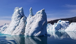 The conical tips of icebergs protrude from the ocean.