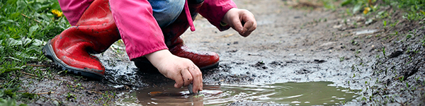child playing in mud puddle