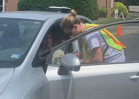 person in high visibility vest leaning into car