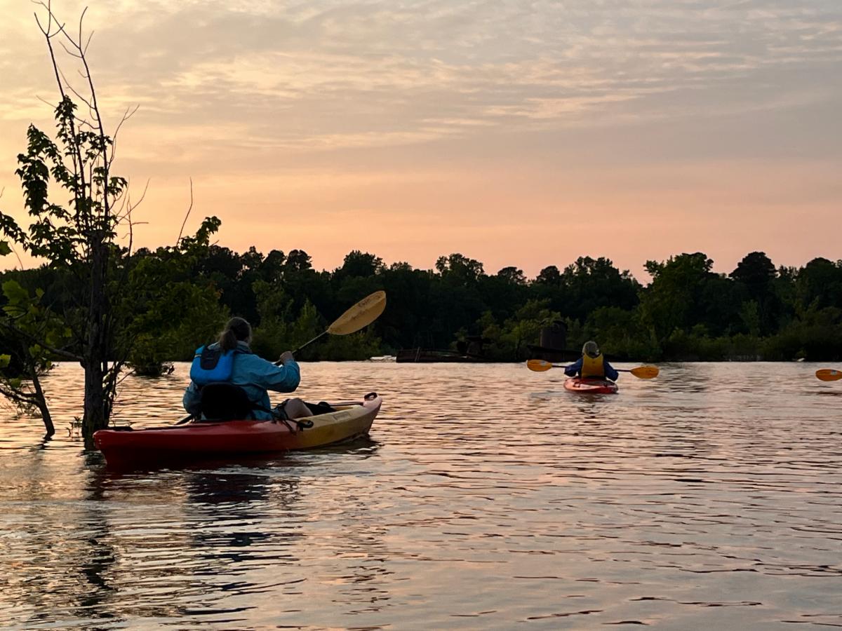 kayakers on water with sunset