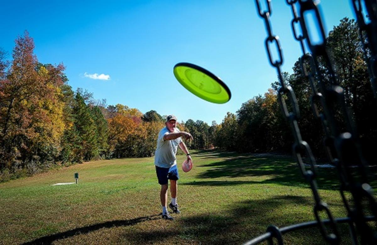 disc golf player throwing disc to chains