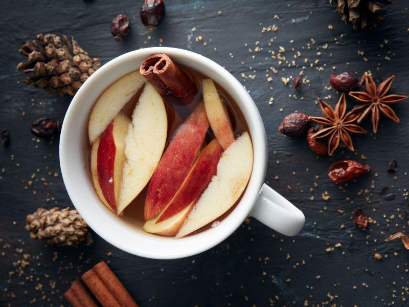 white mug filled with apple slices and cinnamon 
