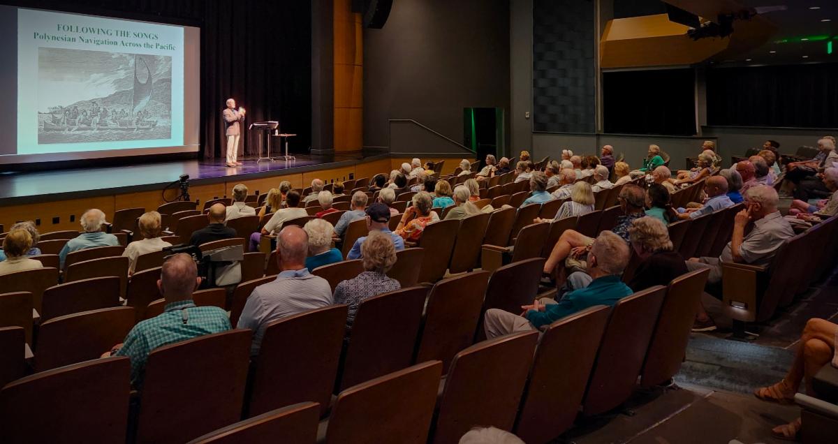 Author and lecturer Robert N. Macomber opens his talk on Polynesian Navigation by sounding his conch shell on stage at The Tribby Arts Center.