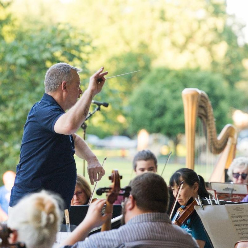 Conductor leading an outdoor orchestra.