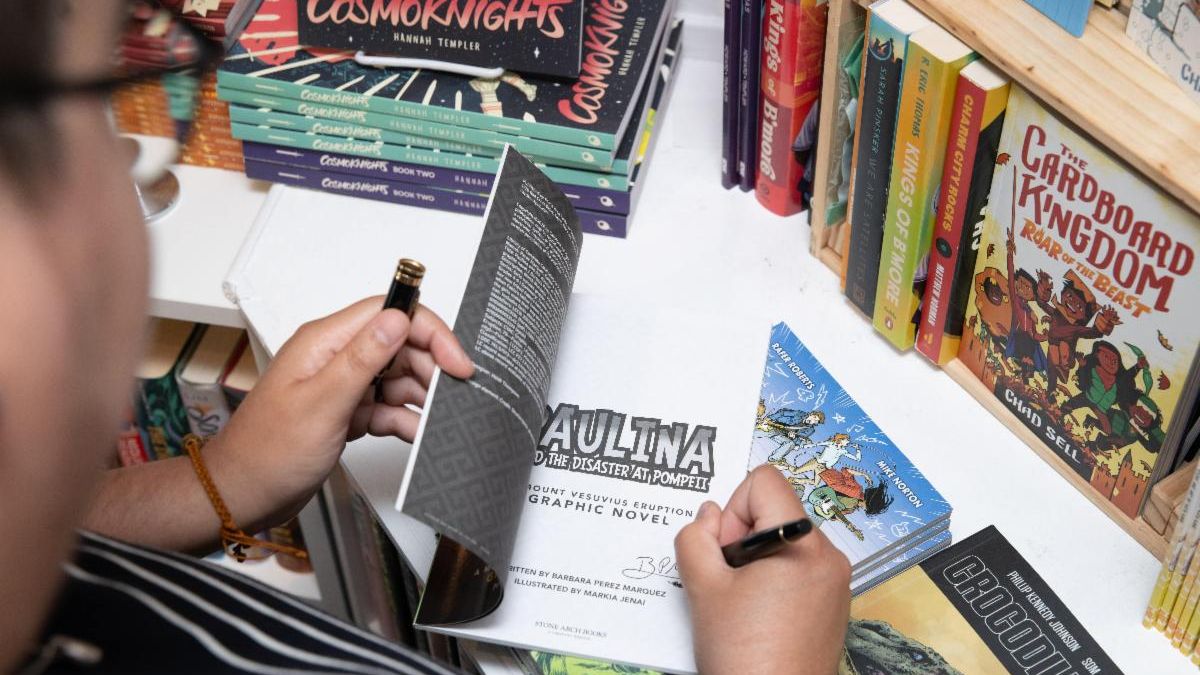 over the shoulder view of Barbara Perez Marquez signing a graphic novel