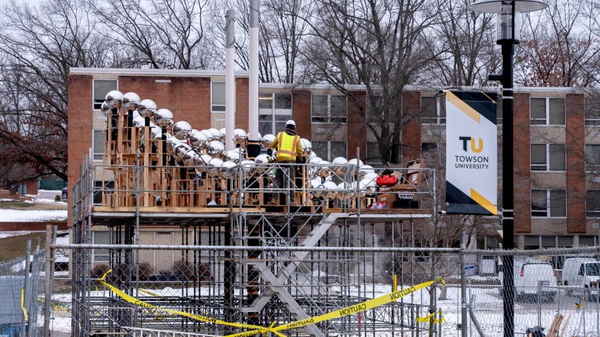 worker in yellow construction vest installating of public art sculpture on scaffolding
