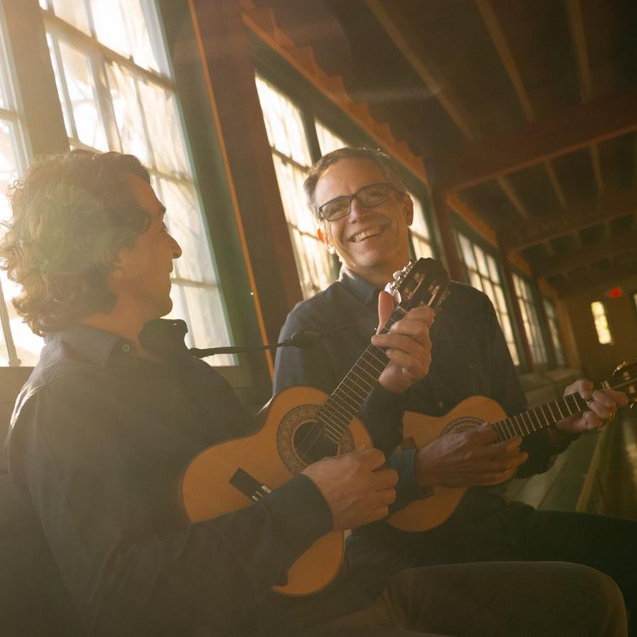 two men laughing with each other while play guitar