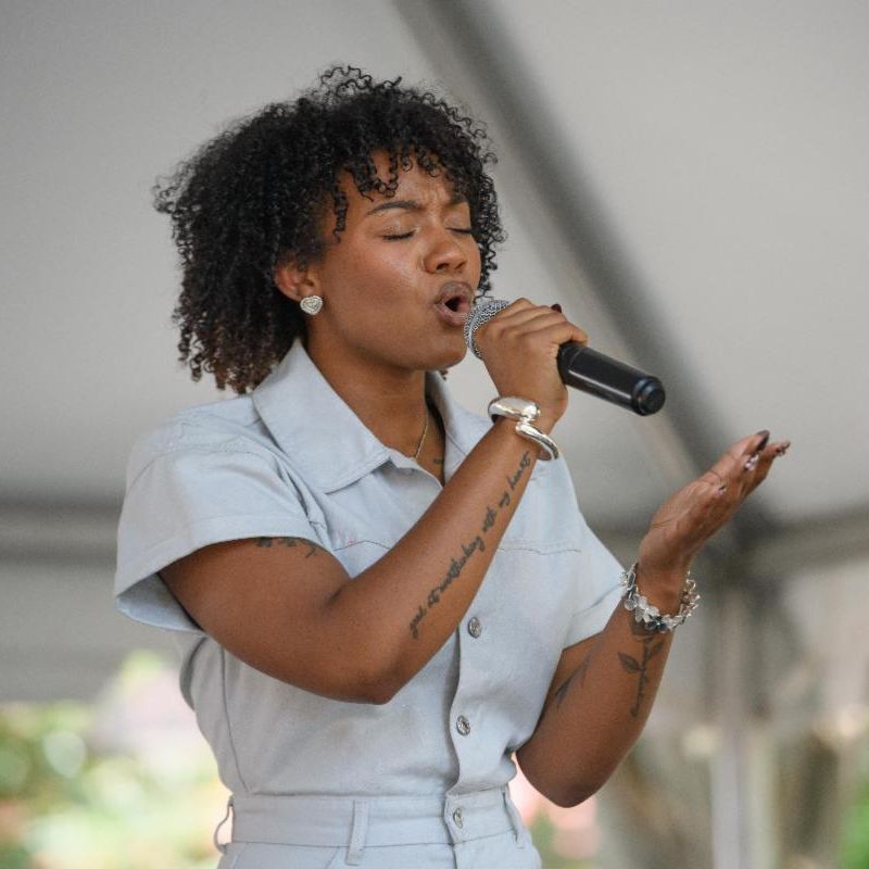 woman singing with eyes closed on outdoor stage