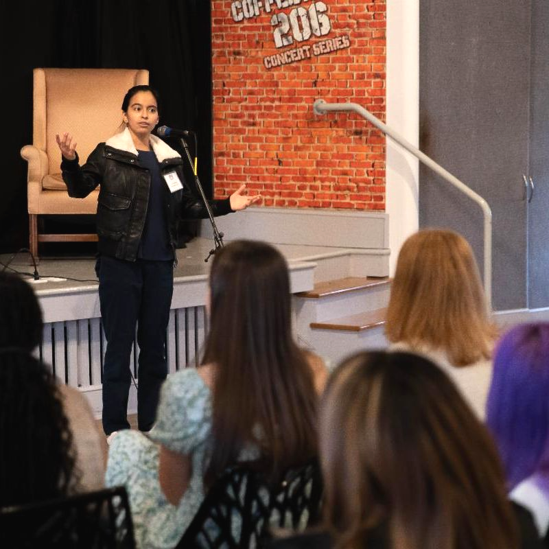 Teenager reciting poem at a microphone during a local competition. Audience watches intently. 