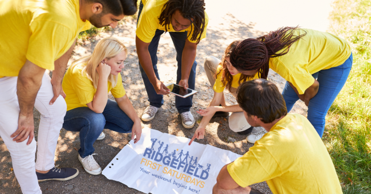 Discover Downtown Dash header image of people working together on a banner that has the Ridgefield First Saturday logo on it