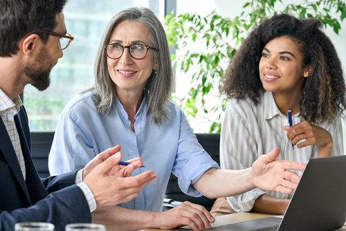 Happy diverse business people group negotiating business strategy at boardroom meeting table using laptop. Multicultural team discuss project developing financial research working together in office.