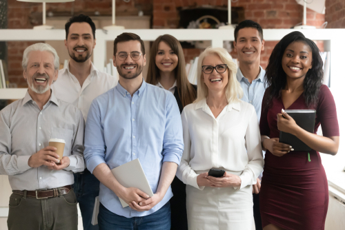 Happy diverse professional business team stand in office looking at camera_ smiling young and old multiracial workers staff group pose together as human resource_ corporate equality concept_ portrait