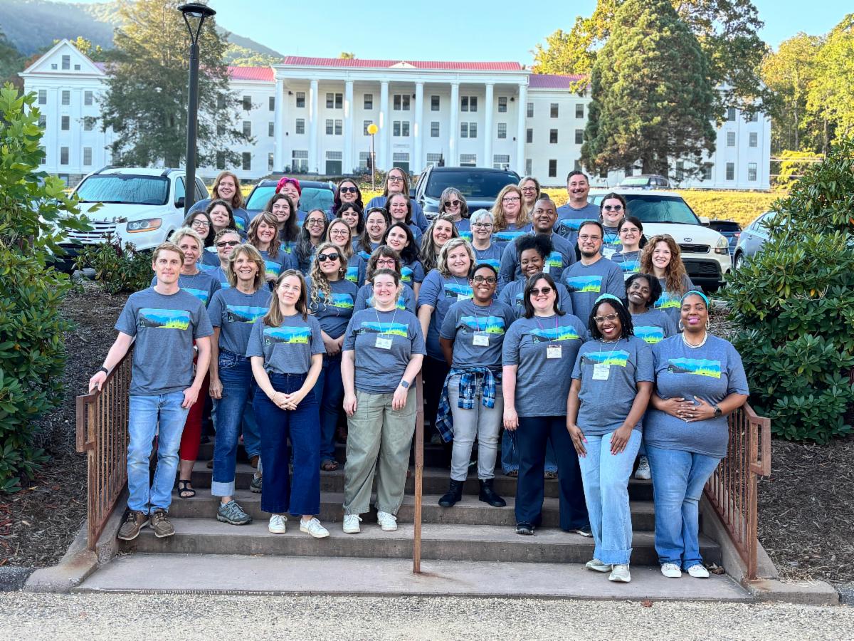 A group of people in matching t-shirts standing on a staircase outdoors.