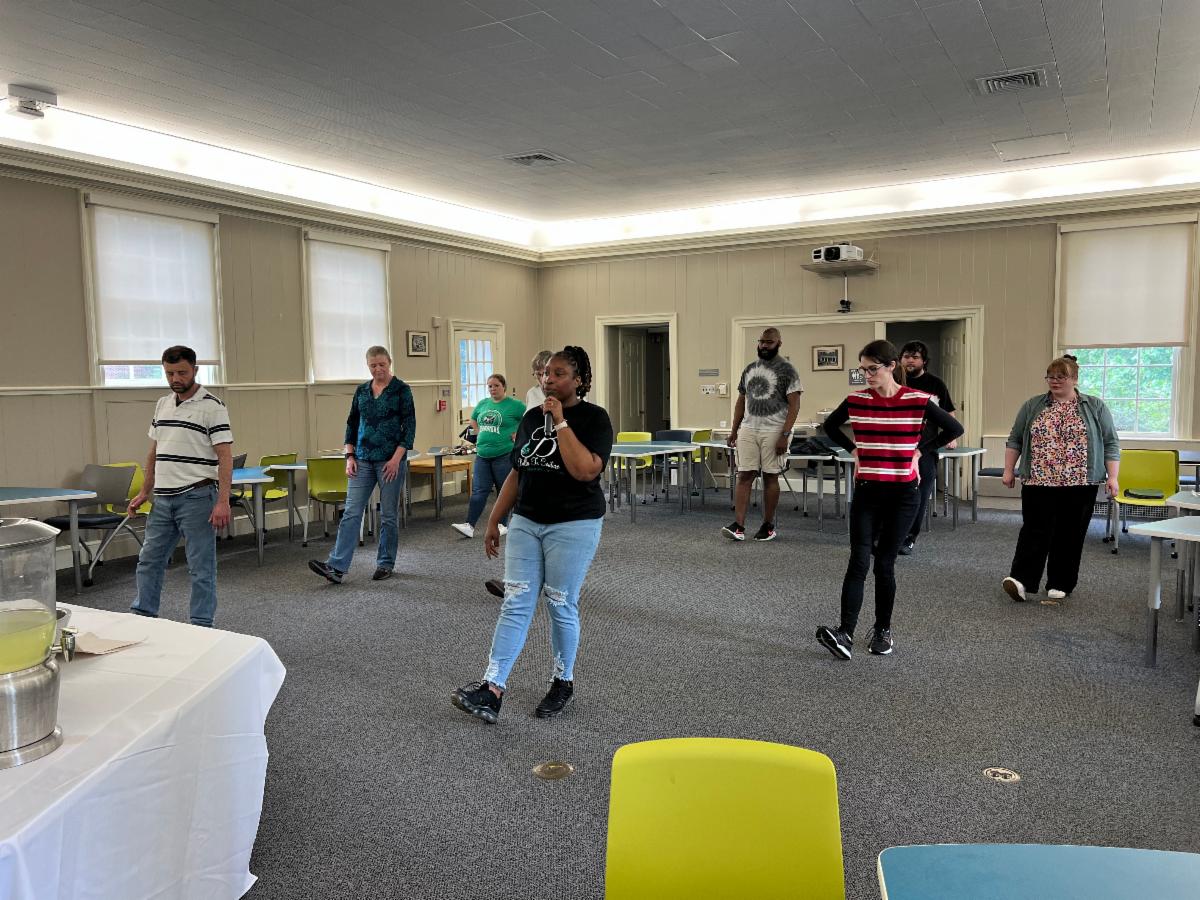 A group of approximately ten people line dancing indoors.