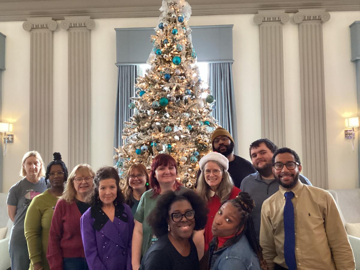 Group of people standing in front of a Christmas tree.