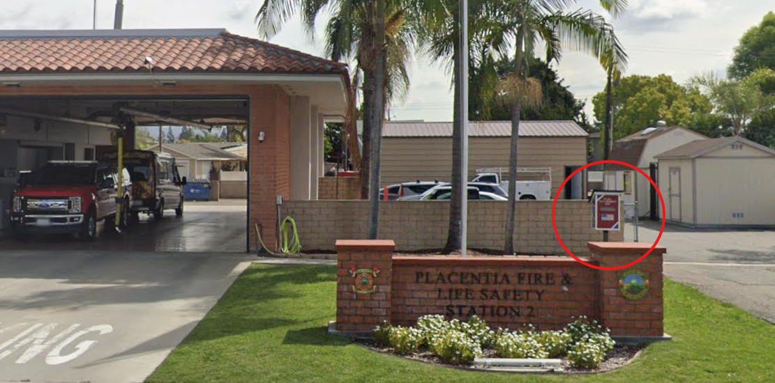 Exterior of Placentia Fire & Life Safety Station 2 with fire trucks in the garage and a red-circled sign near the entrance.