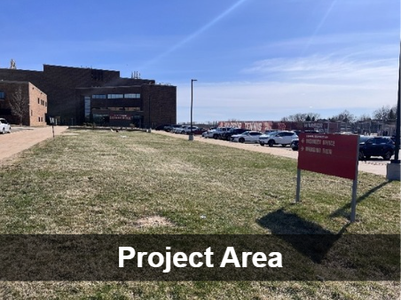 A brick building with a parking lot and large grassy area stretched out in front. Greyed out box near bottom with 'Project Area' in white text.