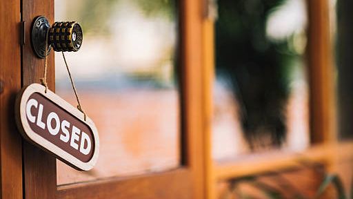 A sign with the text "closed" hangs on a sunny wooden door.