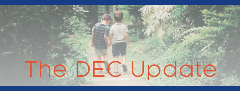 Two children hold hands walking through a path in a forest