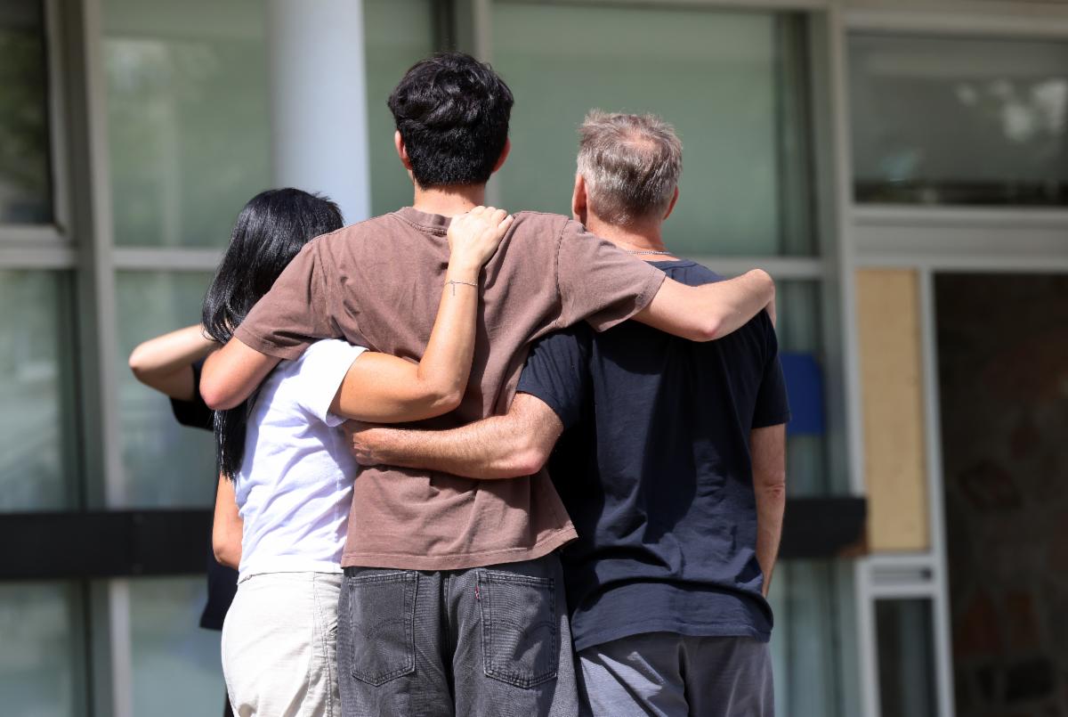 Student and their parents embrace with their backs to the camera.