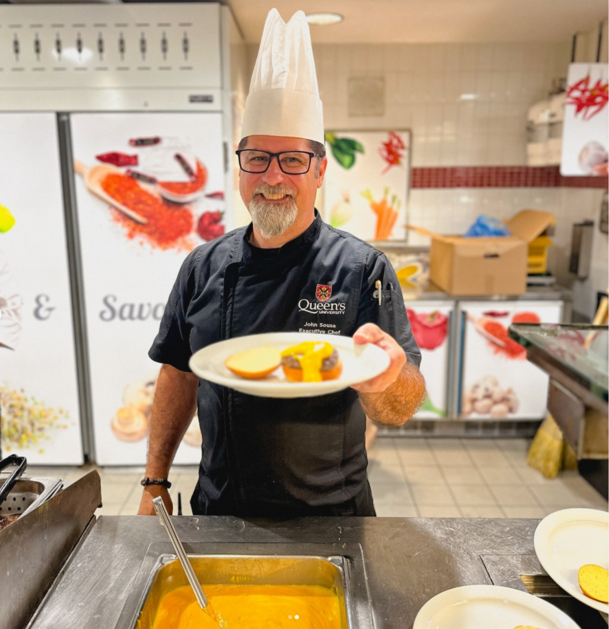 Chef John Sousa smiles and serves a plate of food
