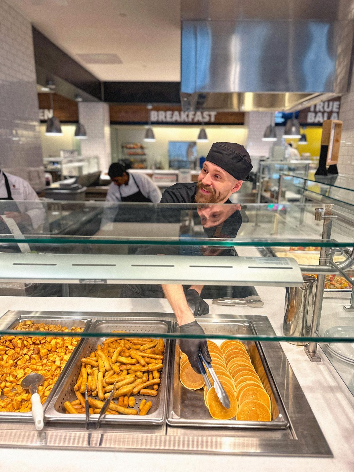 Hospitality staff member smiles ad serves food