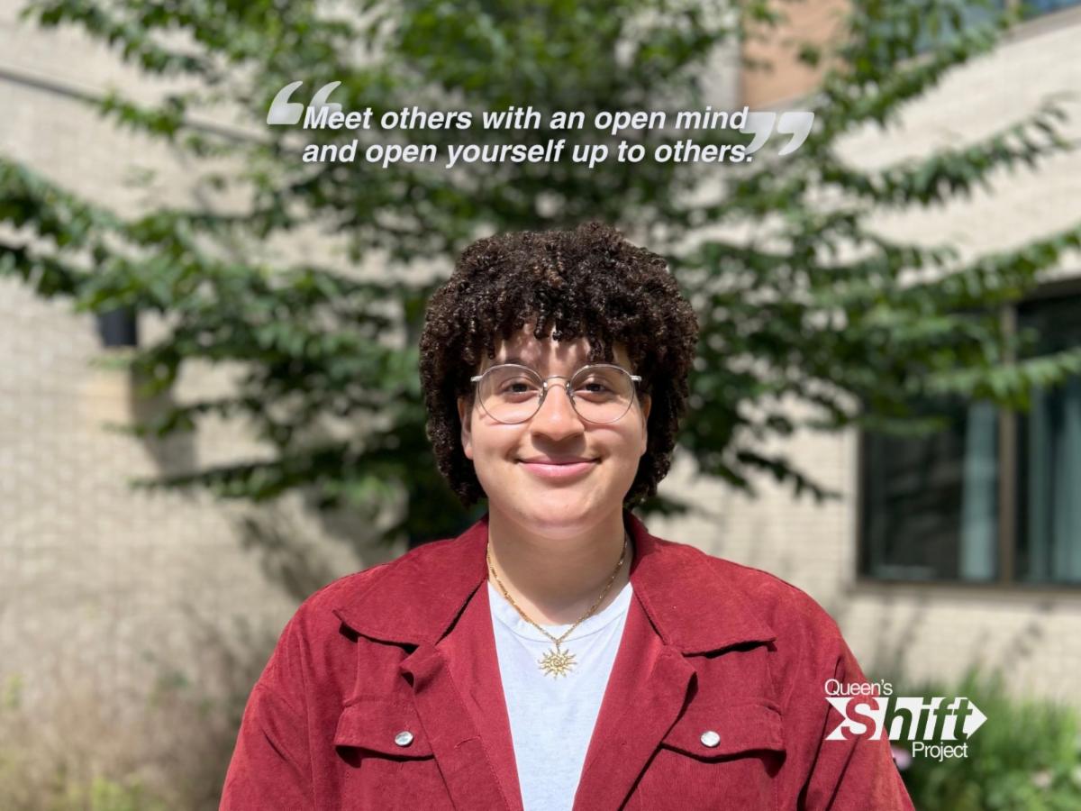 A student, Syd, smiles in the Endaayaan – Tkanónsote courtyard. Text above them reads: "Meet others with an open mind and open yourself up to others."