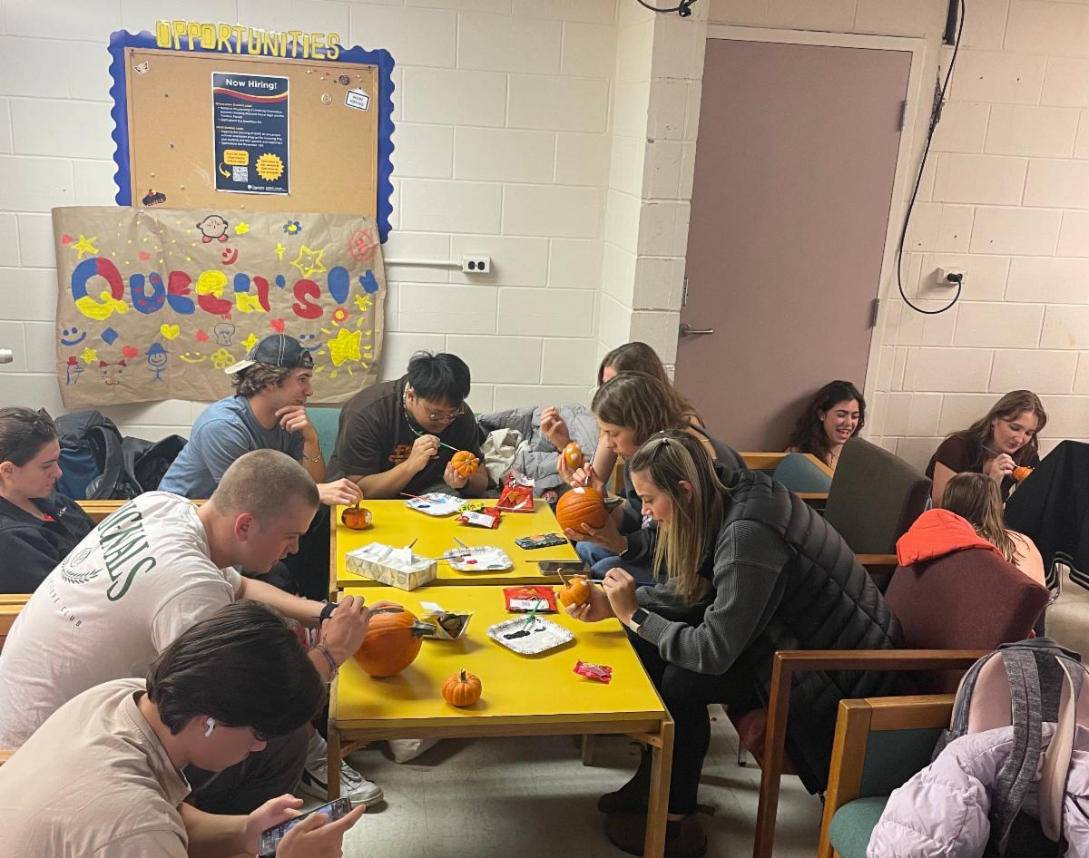 Students paint pumpkins and chat around a shared table