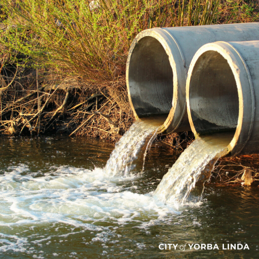 Water flows out of two storm drain pipes into a river.