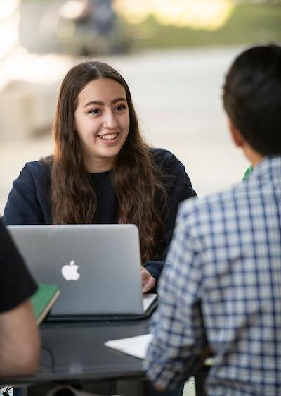 Students smiling while one uses a computer