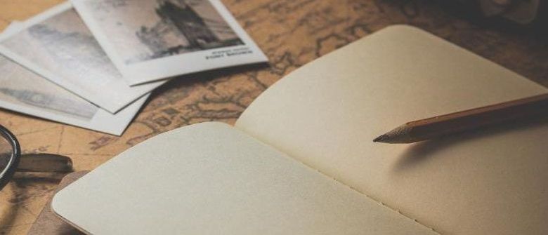 Open notebook with pen and photographs on top of a world map