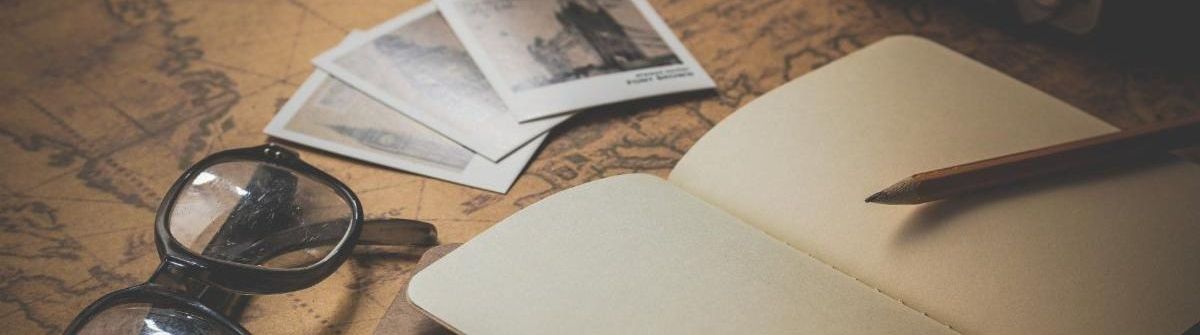 Open notebook with pen and photographs on top of a world map