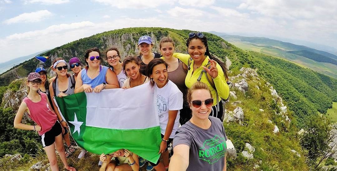 UNT study abroad students holding up the UNT Battle Flag on top of a mountain