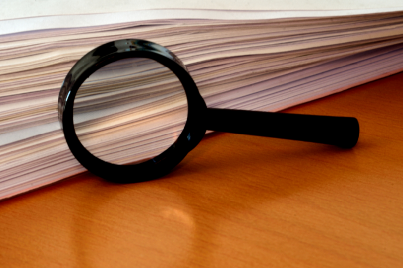 Magnifying class with a stack of paper