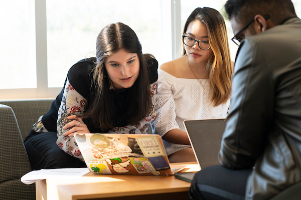 Three students looking at a laptop during a study session at the BLB