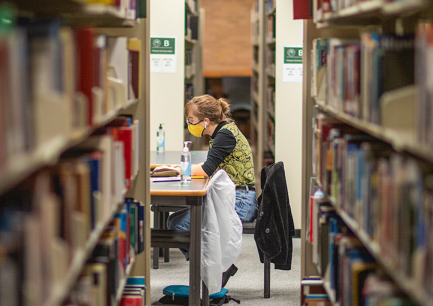 Student studying between book stacks in UNT's Willis Library