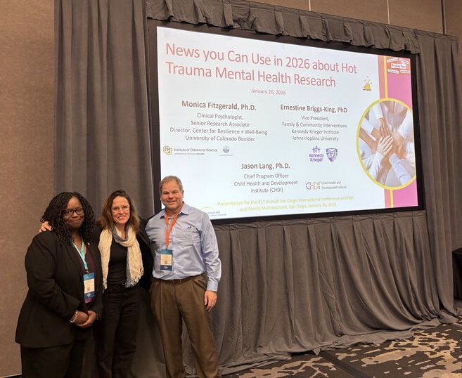 Jason Lang poses with 2 colleagues in front of projector screen at conference